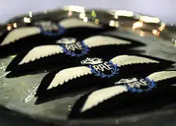 Four RAF badges in a row, each showing letters RAF, inside a blue laurel, with a crown above it and wings to either side