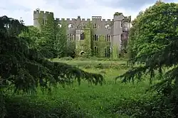 a ruinous castle with trees and grassland
