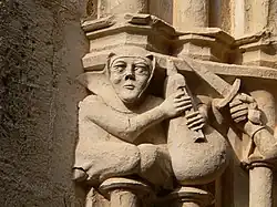Detail of a figure with bagpipes carved on a capital in the cloister