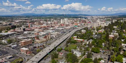 Aerial view of Spokane with a large freeway in the foreground and mid-rise buildings in the background
