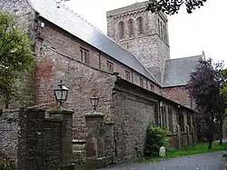 A stone church seen from an angle, with a clerestory and a large central tower with a plain parapet