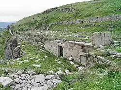 Stone remains of a building, lying on a grassy hill