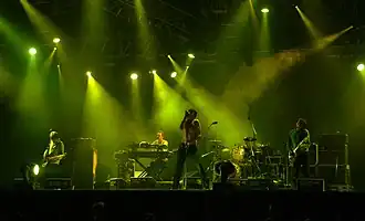 Several men performing onstage playing and singing into a microphone