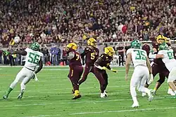 Jayden Daniels preparing to throw a football in a college football game