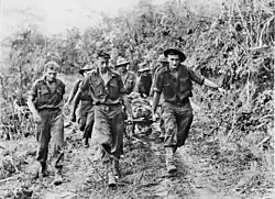 Soldiers carry a stretcher upon which another man lies