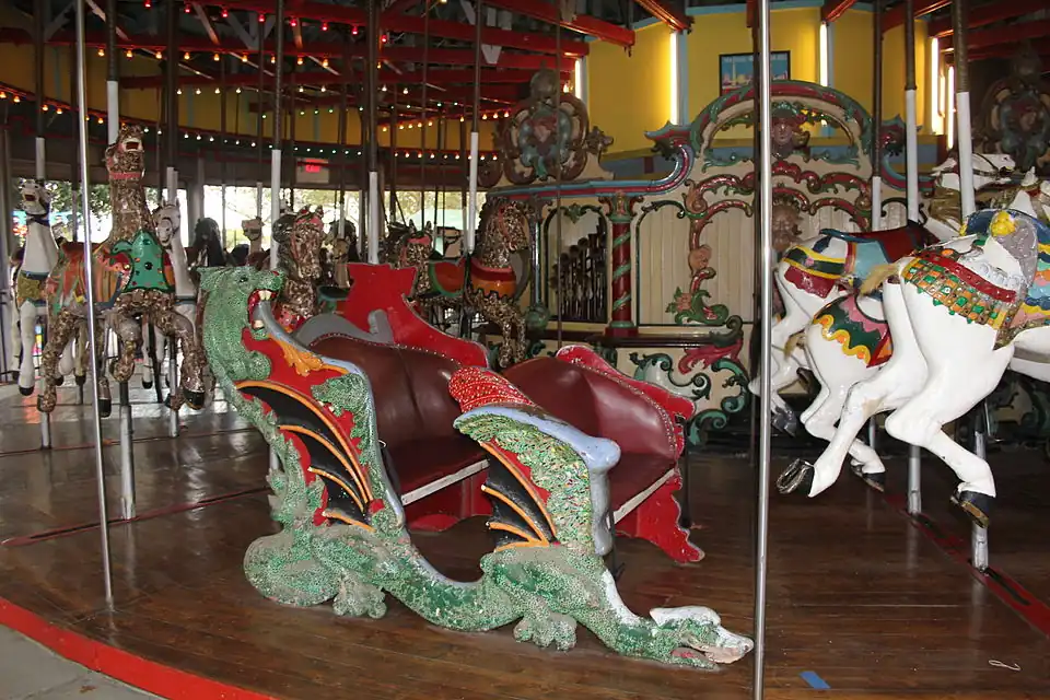 A green dragon chariot with red seats on a historic carousel