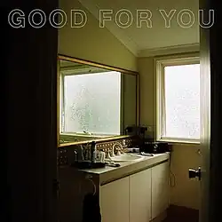 Photo taken from inside a bathroom, with light shining from the window inside. The song name is in capital letters at the top.