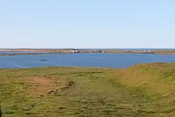 A body of water with scattered buildings in the distance on the other side