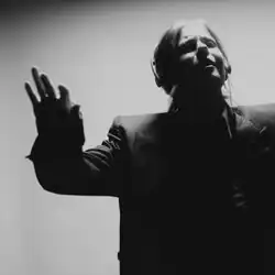 Black and white photograph of Haley Blais with her right hand extended outwards and her head facing upwards.