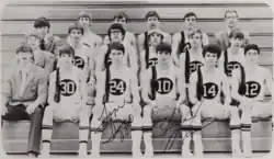 Basketball players sitting on bleachers wearing uniforms