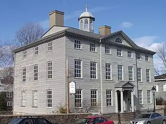 This gray three story mansion is topped by a small windowed turret.