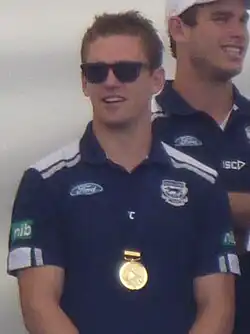 Selwood wearing sunglasses and premiership medal, standing in front of another member of the team