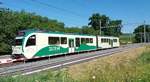 Green and white electric train at a station