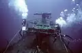 U.S. Navy divers measuring the deck gun in 1987 as part of Project Sea Mark for Navy historic sites