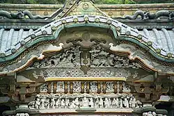 White carved figures under an undulating gable.
