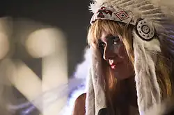 Oh Land is performing live, wearing a headdress and facing her body to the left.