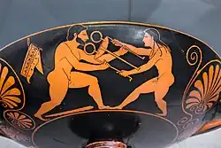 Two nude male figures pull oppositely at a three-legged metal object: Heracles, on the left, is bearded, while Apollo, on the right, has long hair and is clean-shaven.