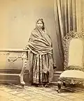 Portrait of a girl from Sindh wearing Sindhi Choli (tunic), Sossi Shalwars under Satin Paro (skirt) with long wide veil, and traditional Sindhi "Tauran wari Jutti"(1870s).