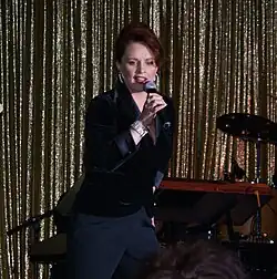 A red-haired woman wearing a dark blue shirt and pants is performing